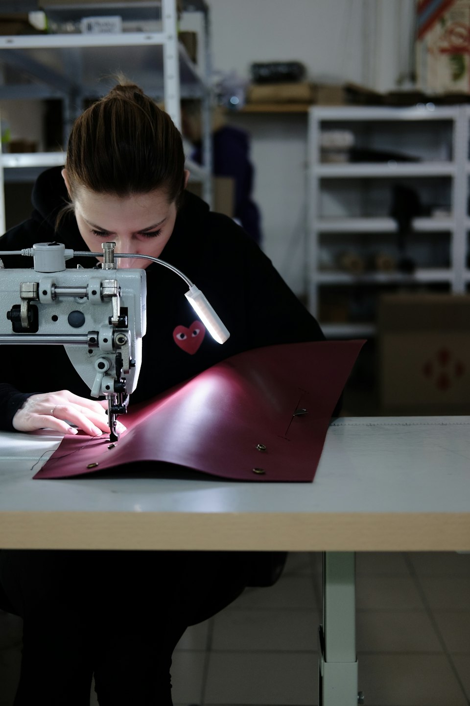 Mujer cosiendo cuero rojo en una máquina de coser.